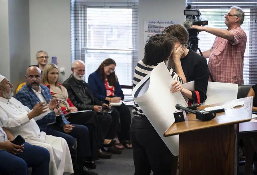 A woman kisses her partner during public comment in Hamtranck City Hall — Photo by Sarahbeth Maney,/ Detroit Free Press via AP