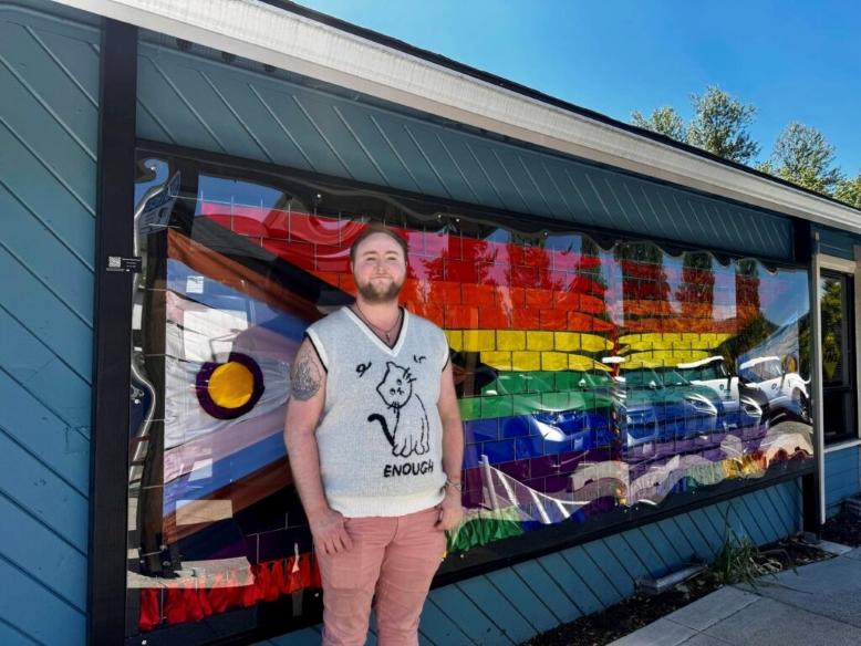 Axton Burton in Front of Intersex-Inclusive Progress Pride flag ribbon art - Photo by Grace Gorenflo